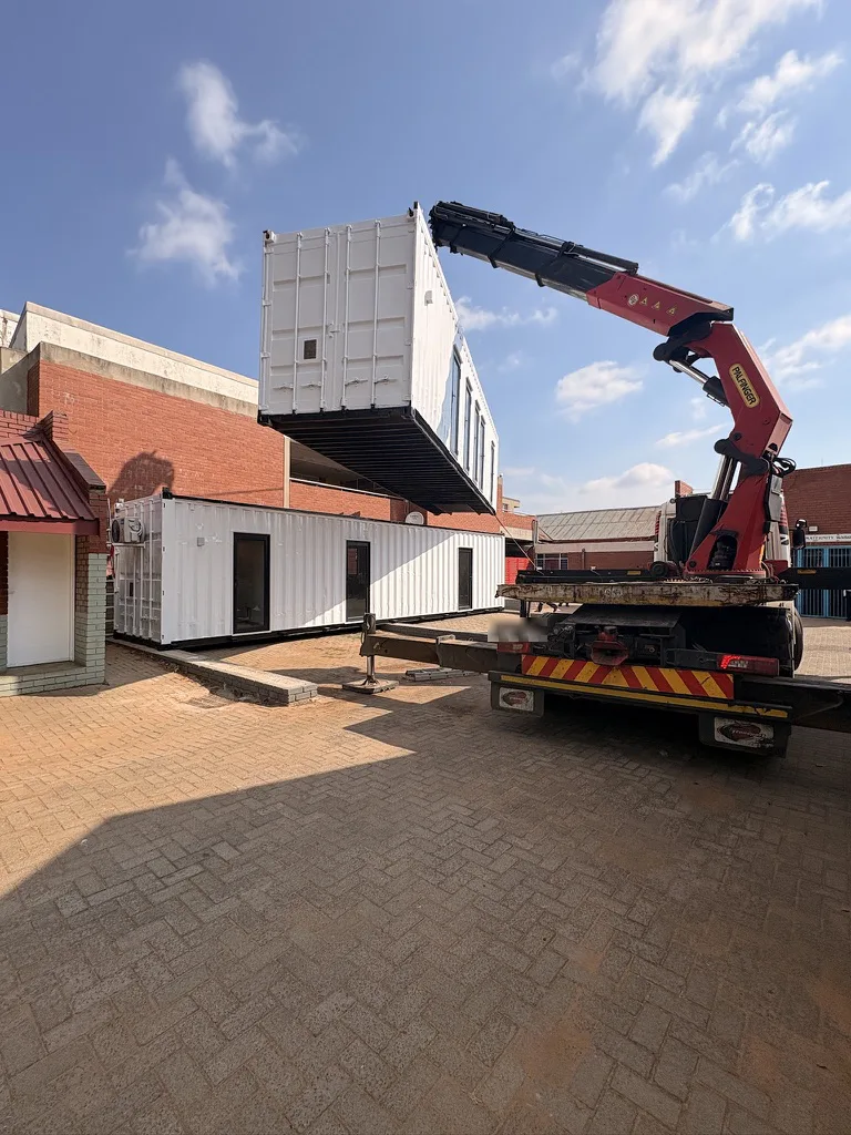 Crane truck lifting a container conversion into place